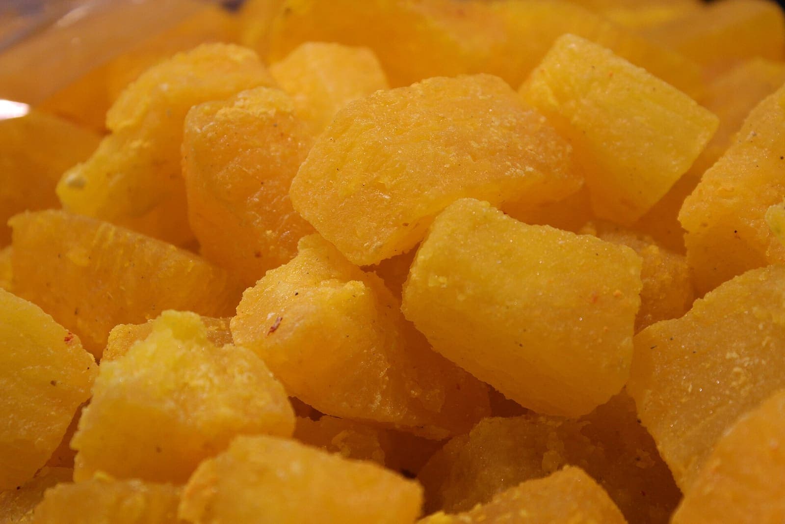 A close-up of saffron-yellow kesar petha, Agra’s candied ash-gourd sweet, in sugar-dusted cubes