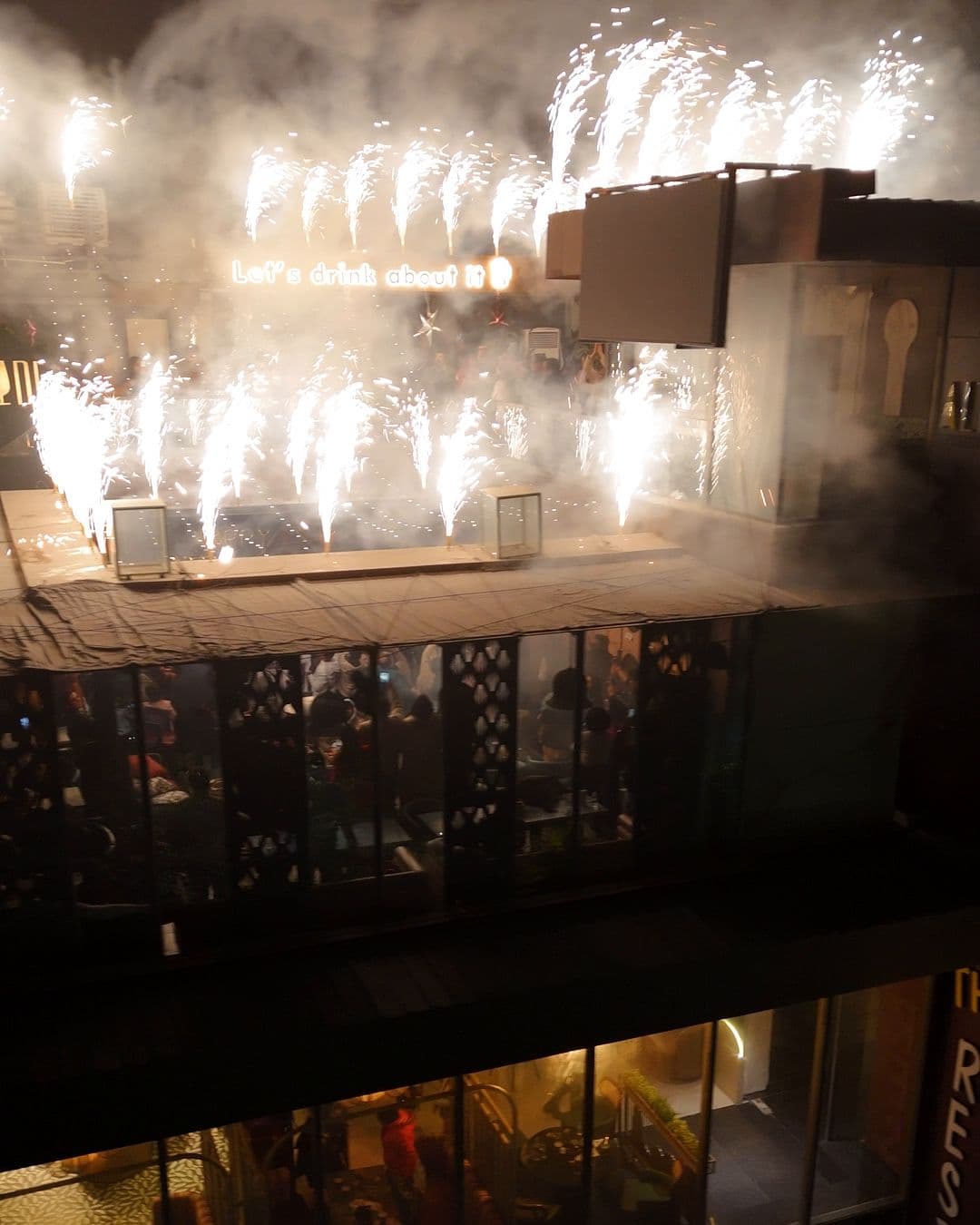 Fireworks going off all along the edge of the Altitude roof at midnight on New Year’s Eve 2025, smoke rising over the terrace