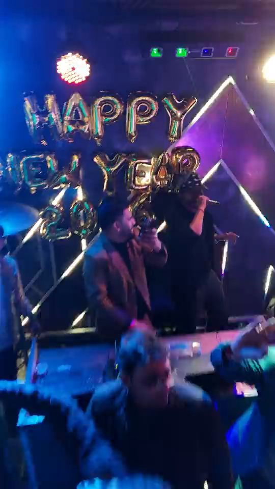 New Year’s Eve at Altitude: the DJ at the decks under HAPPY NEW YEAR 2026 balloons, the crowd with its hands up, and the full dance floor from the side and from straight above